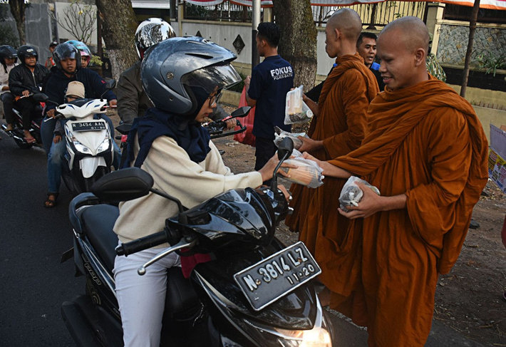  In celebration of the Vesak holiday, Buddhist monks distribute packages of sugary delicacies for breaking the fast, known locally as ‘tajil’, to people passing the Dammadipa Arama Vihara in Batu, Malang, East Java, on Tuesday. (JP/Aman Rochman)